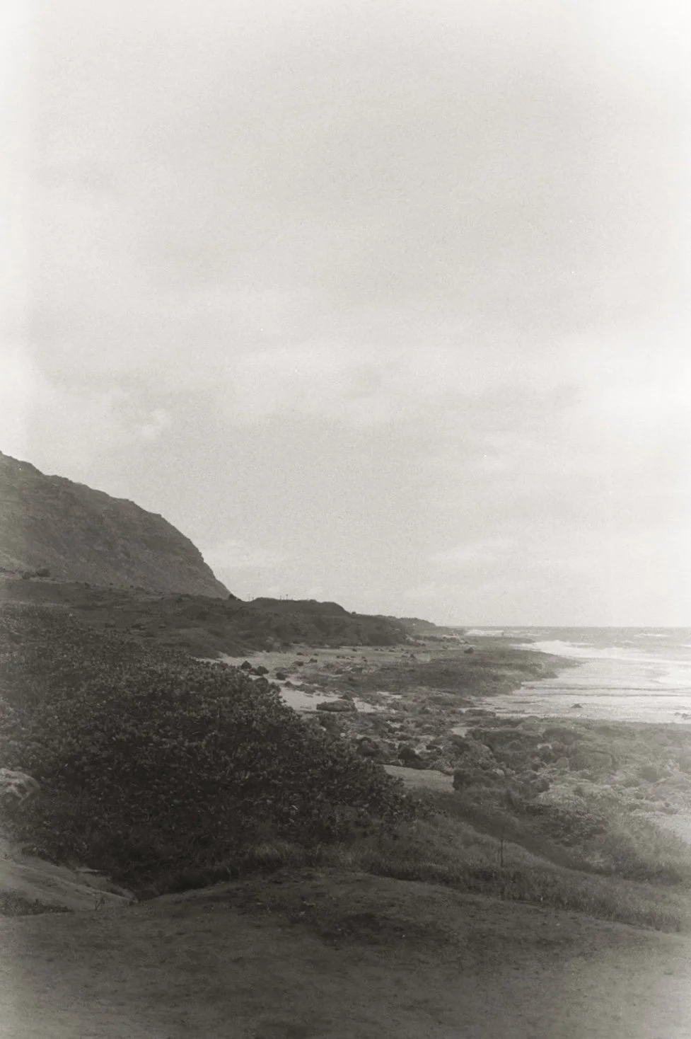 Black and white photo of a coastline with cliffs, beach, and ocean waves.