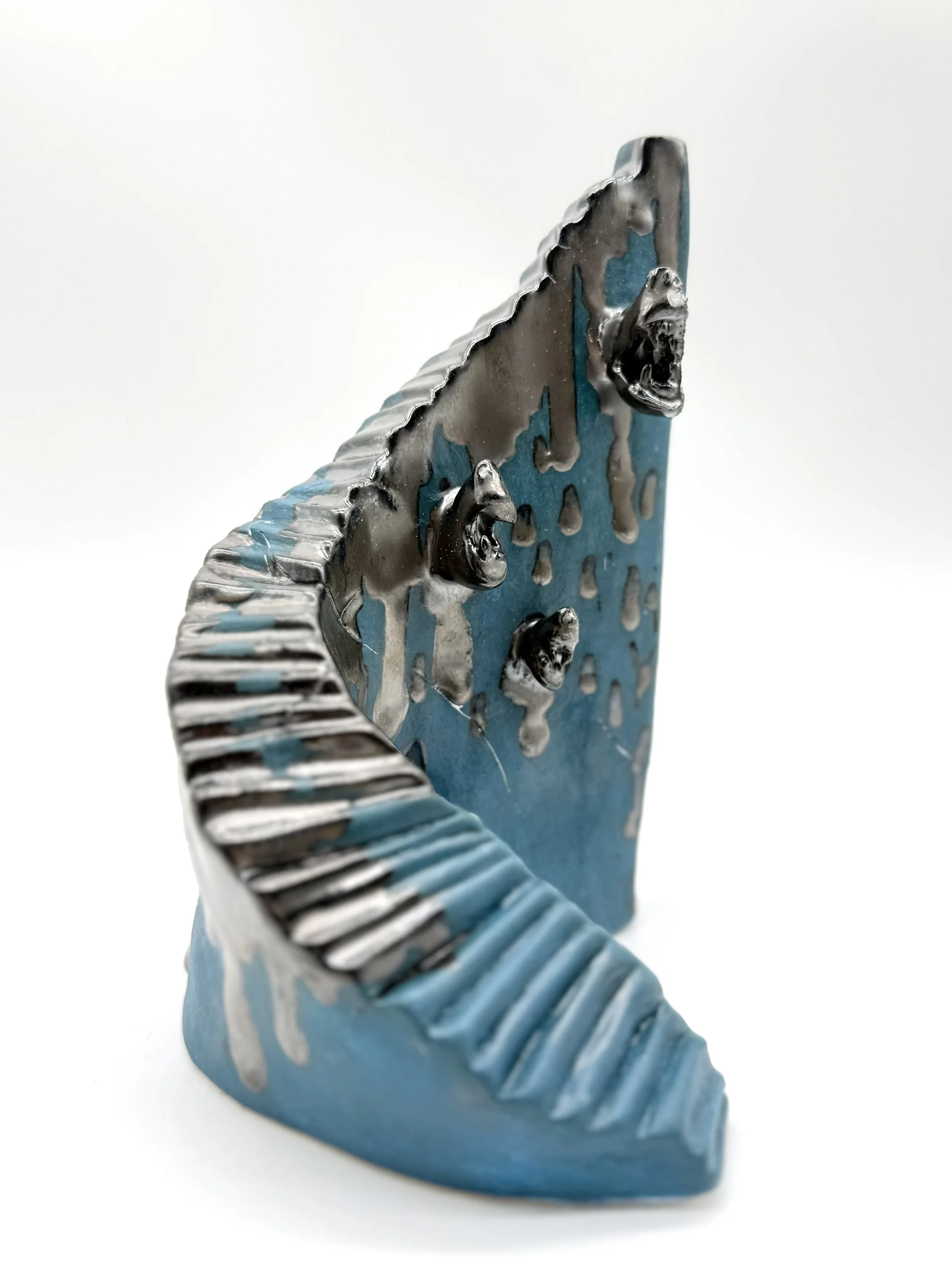 Close-up of a decorative object resembling a dinosaur, painted in blue with silver accents, featuring detailed ridges and an open mouth.