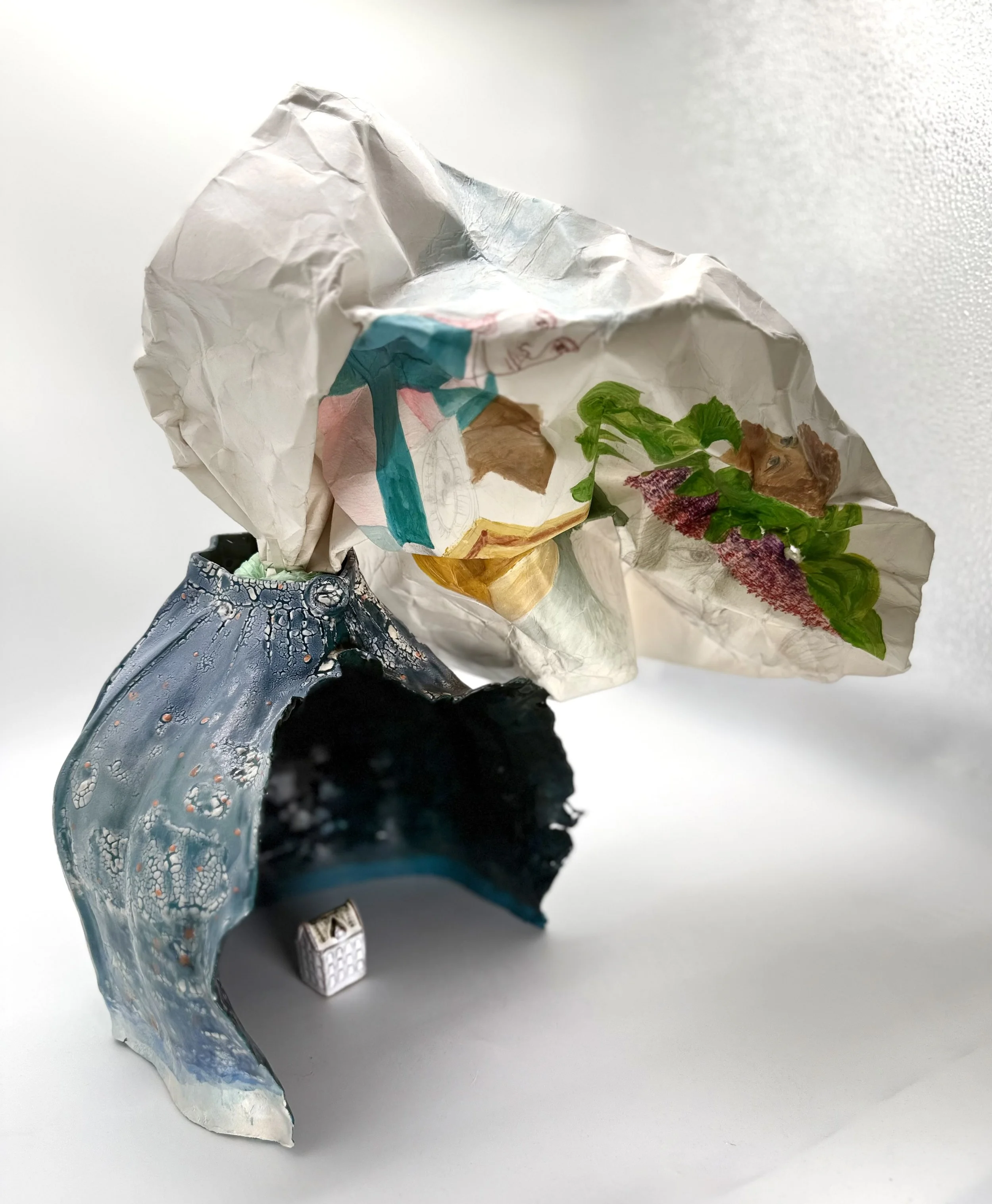 Crumpled piece of paper with a colorful fish illustration and a small silver electronic device on a plain white surface.