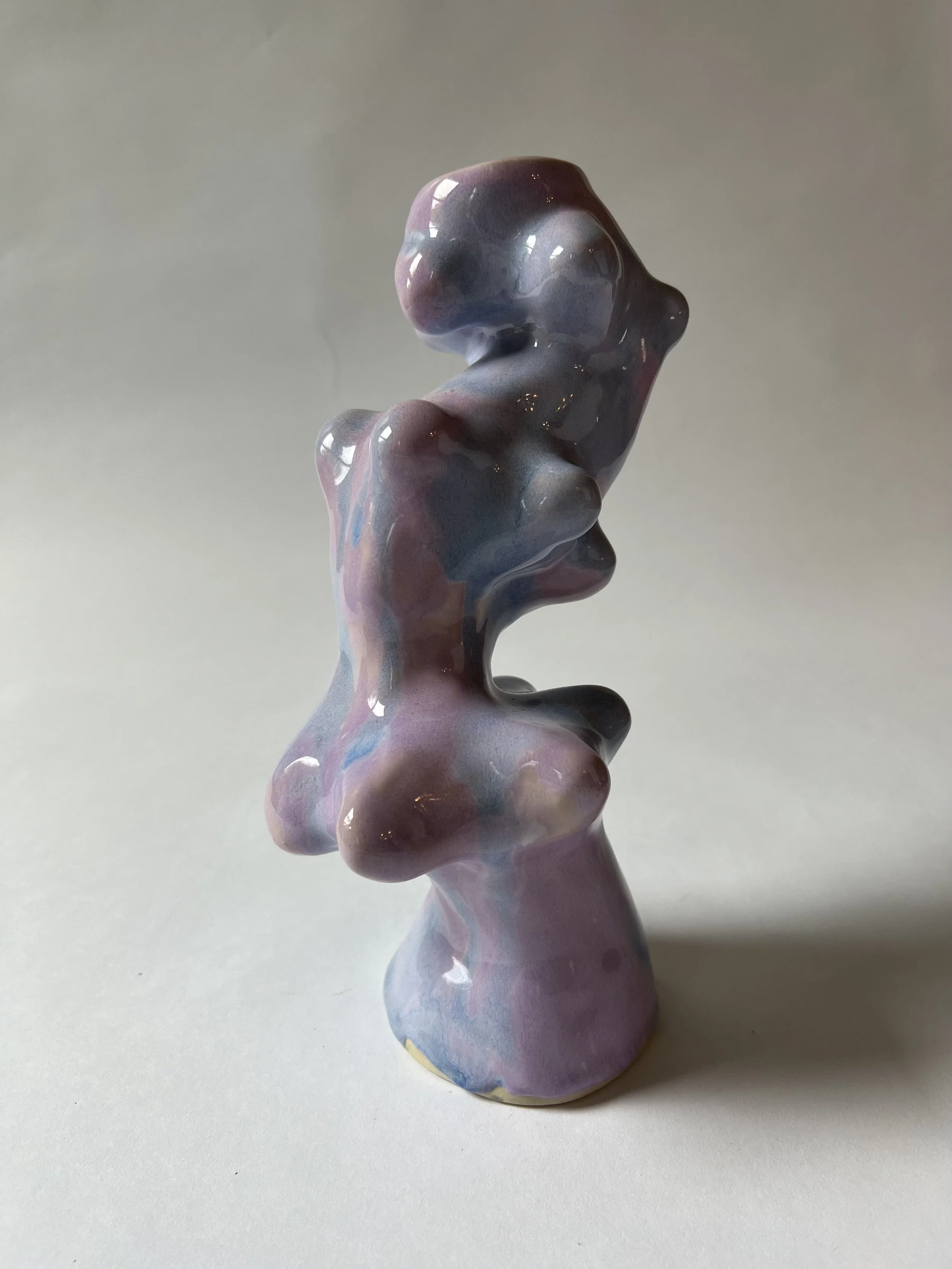 A multicolored ceramic figurine of an abstract human torso, with a glossy finish, placed on a plain white surface.