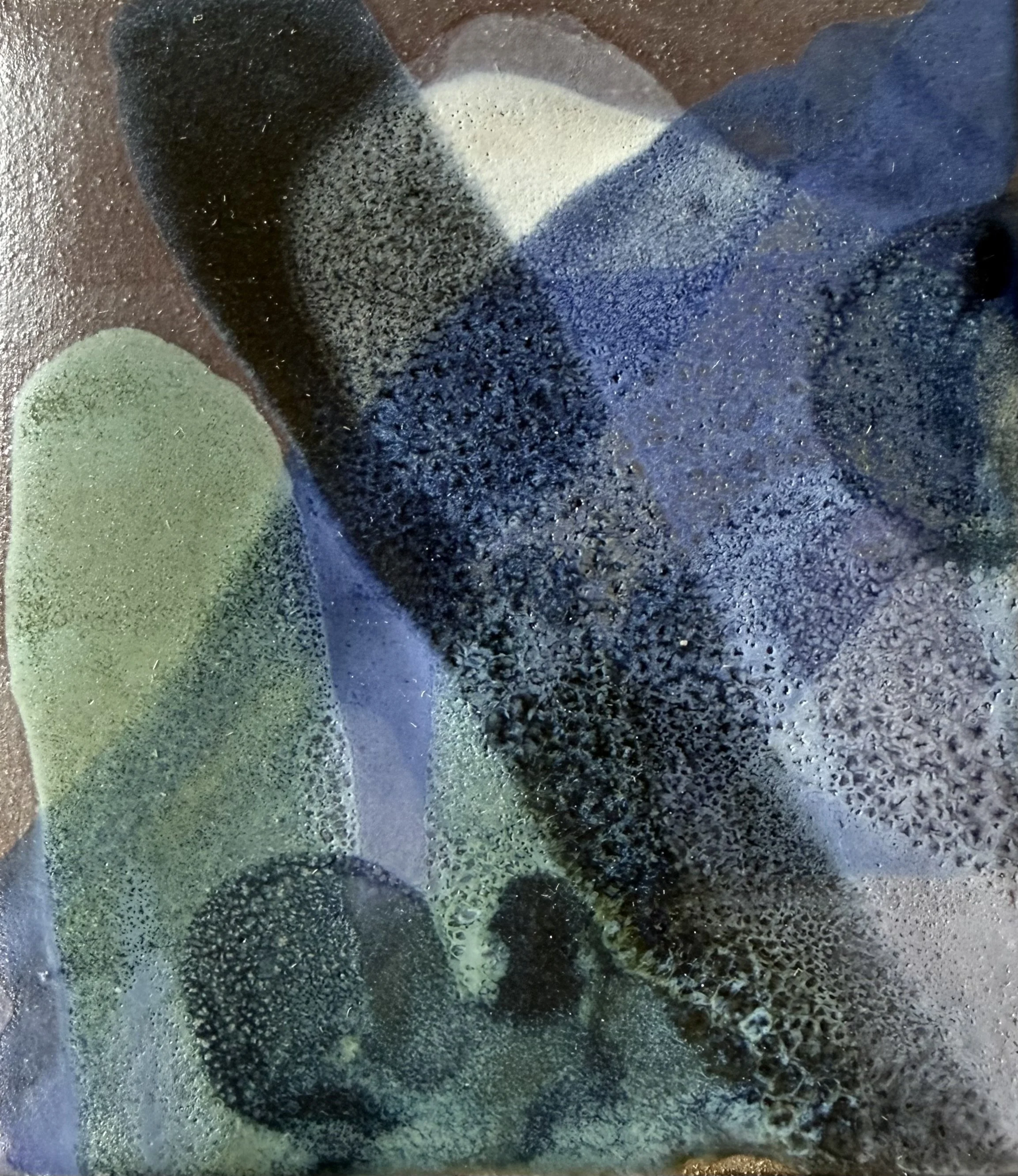 Close-up of a textured surface with various shades of black, green, and beige, resembling a painted or artistic surface with a rough texture.