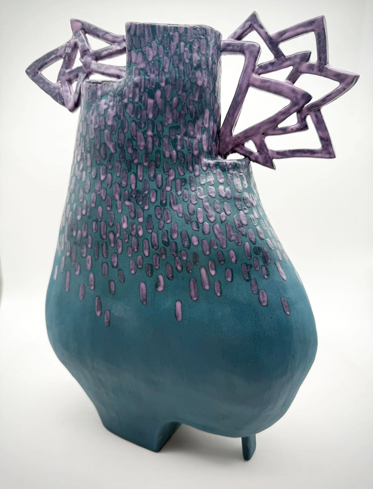 Ceramic vase with a textured teal body and purple geometric star-shaped handles.