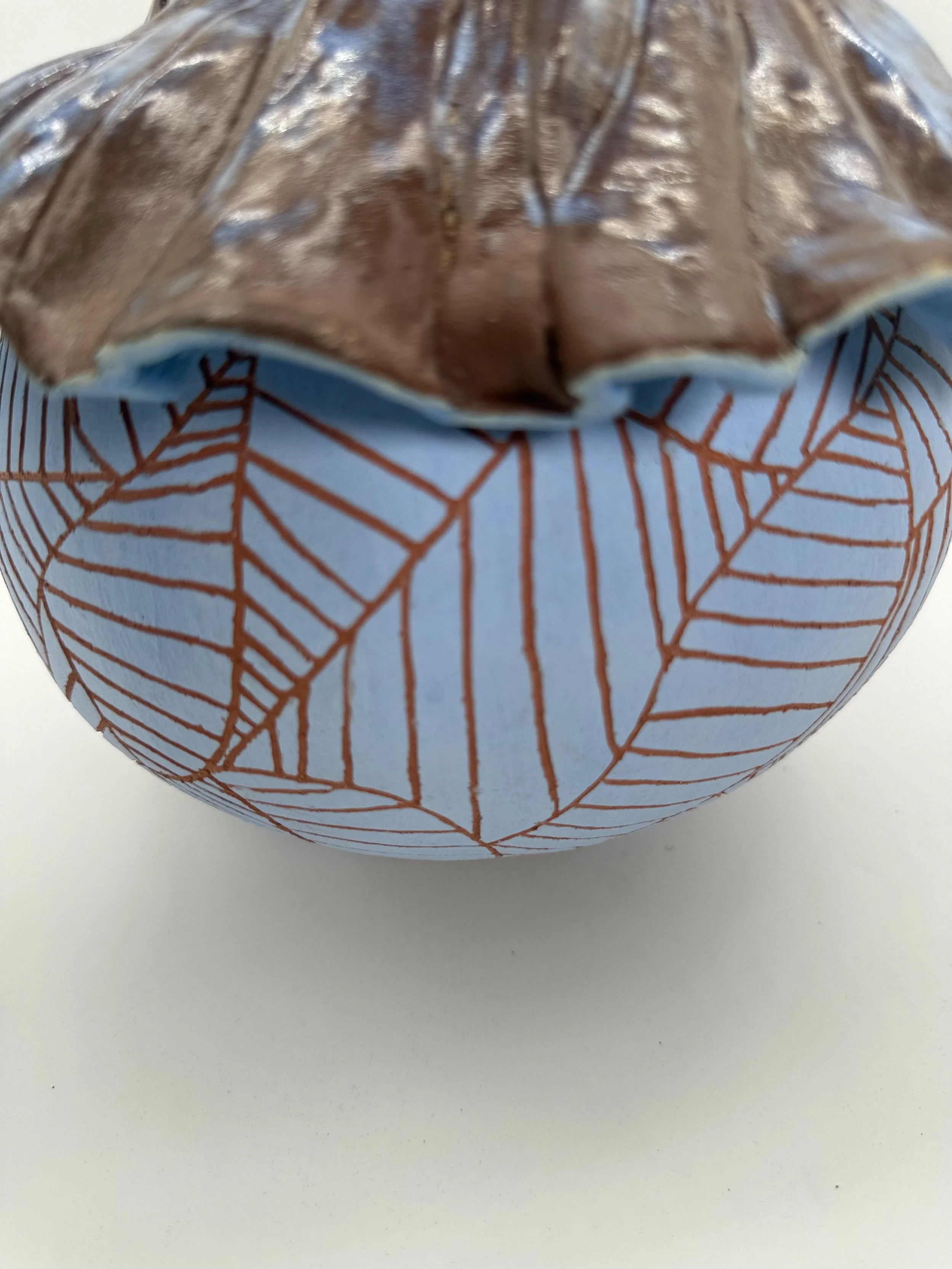A partially unwrapped chocolate bar inside a wrapper with a blue background and orange geometric lines, placed on a white surface.