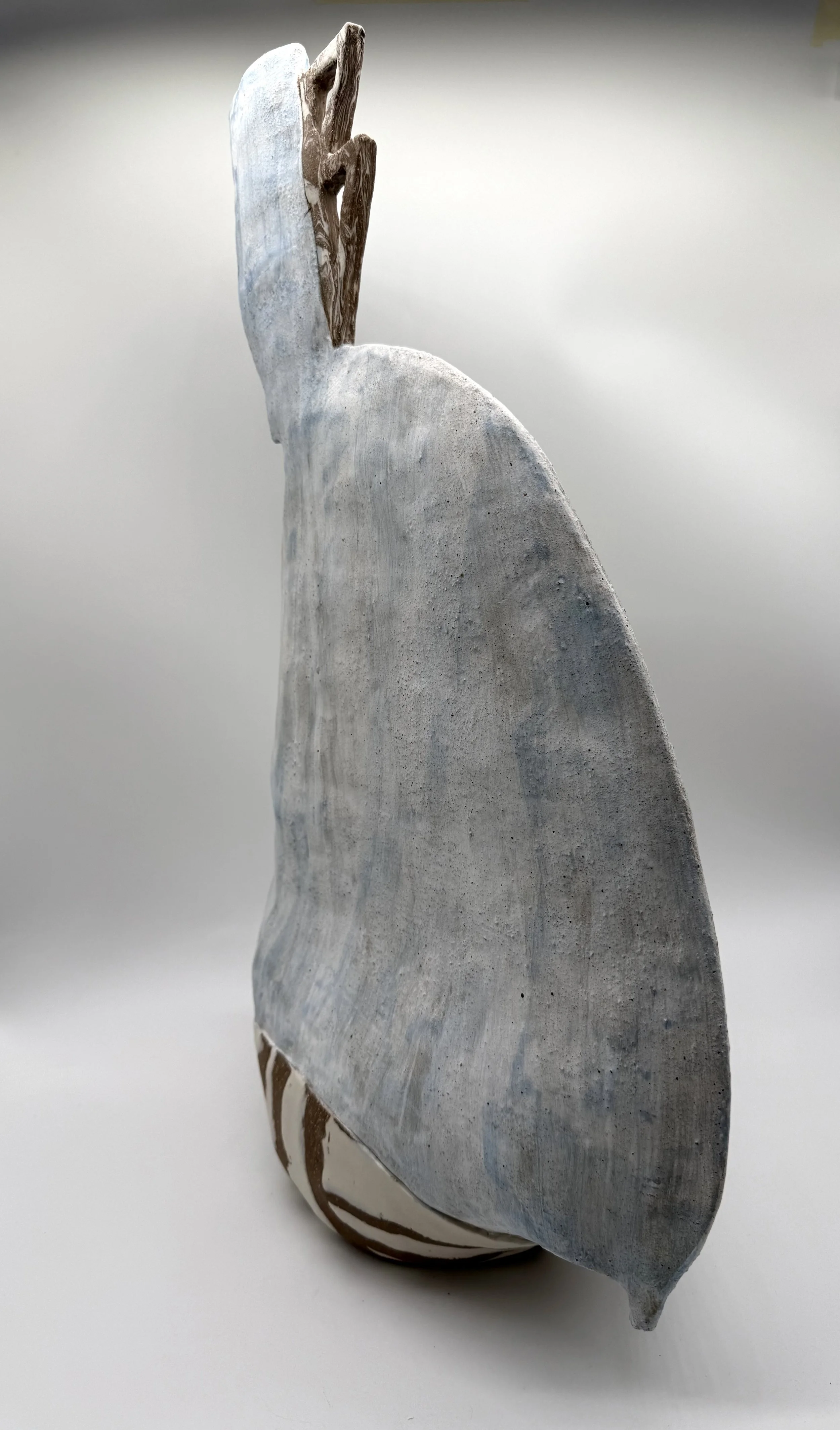 A rock with a smooth, flat surface and a rounded shape leaning against a similar rock, both with light surface texture and some streaks of darker color