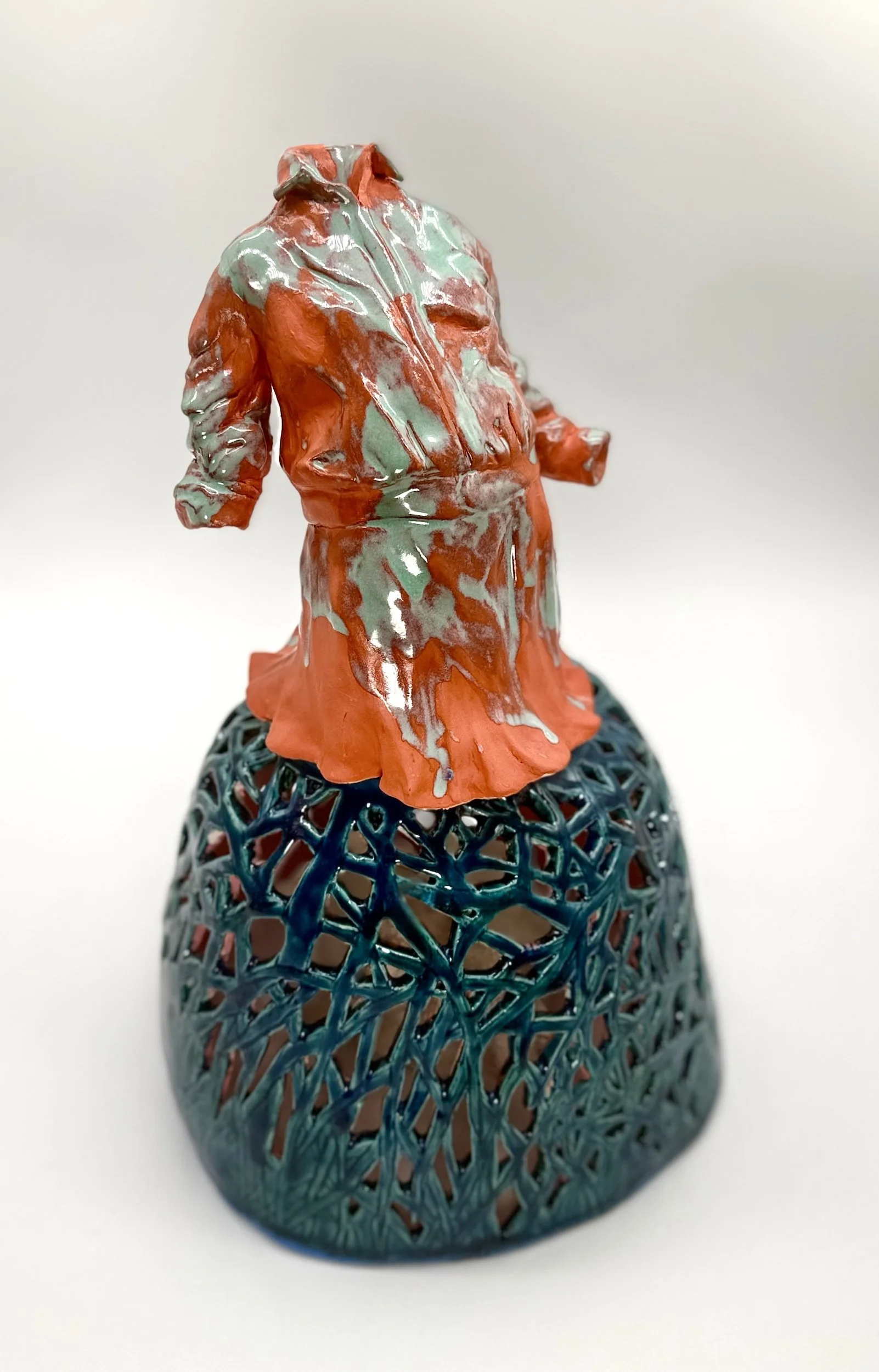 Ceramic sculpture of a person wearing a jacket, standing on a lattice-like blue spherical base.