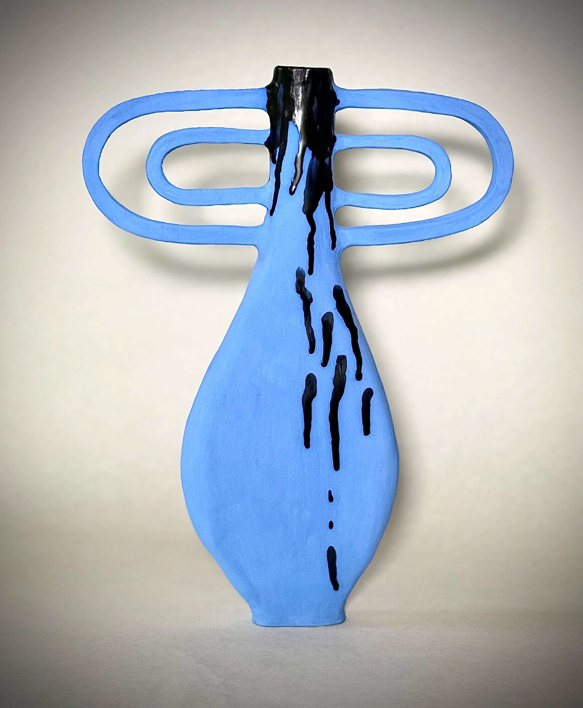 Blue paper cutout in the shape of a hand with black liquid dripping from the top center.