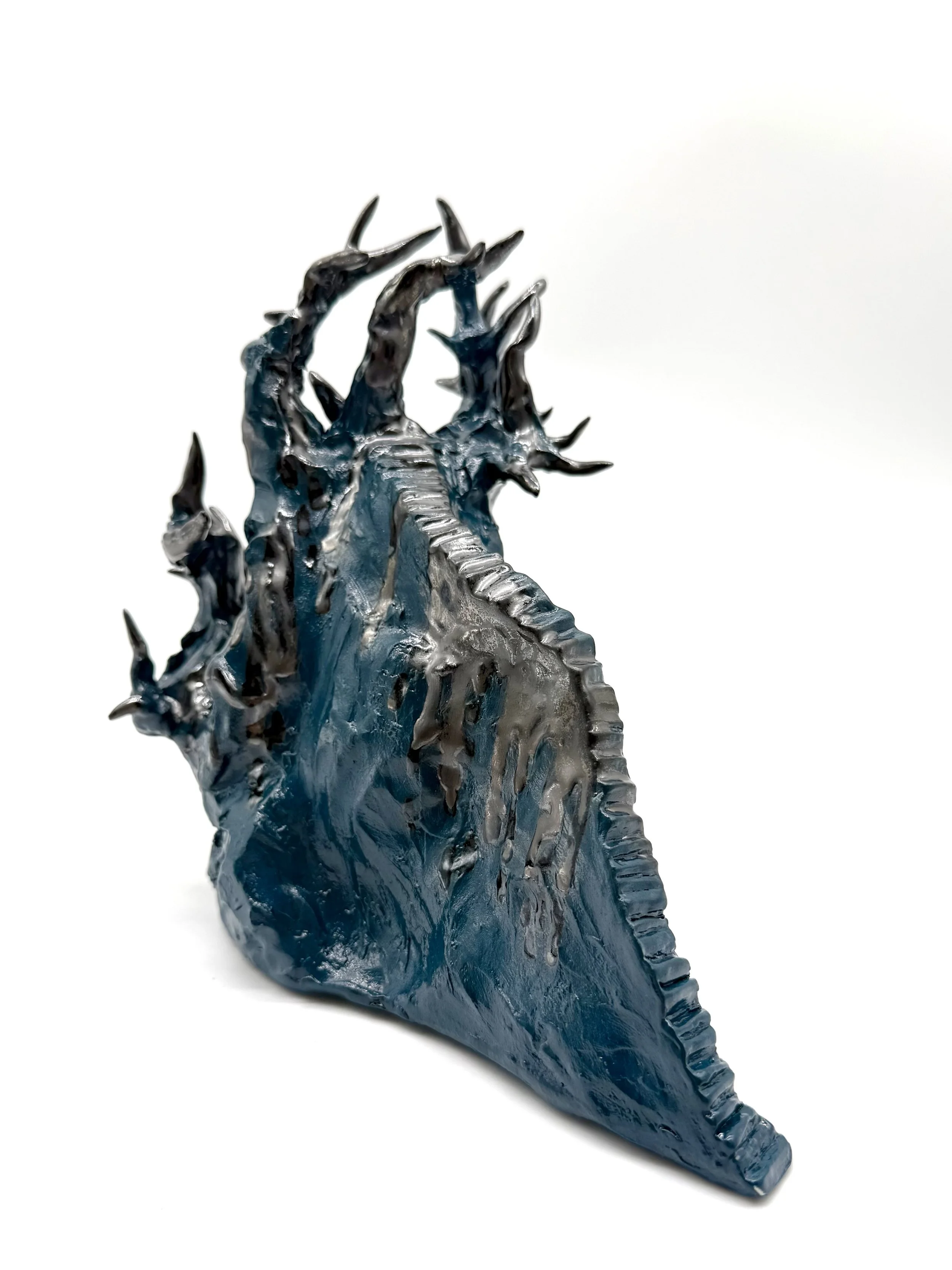 A close-up view of a blue and black plastic dragon figurine with detailed scales and spikes, set against a plain white background.