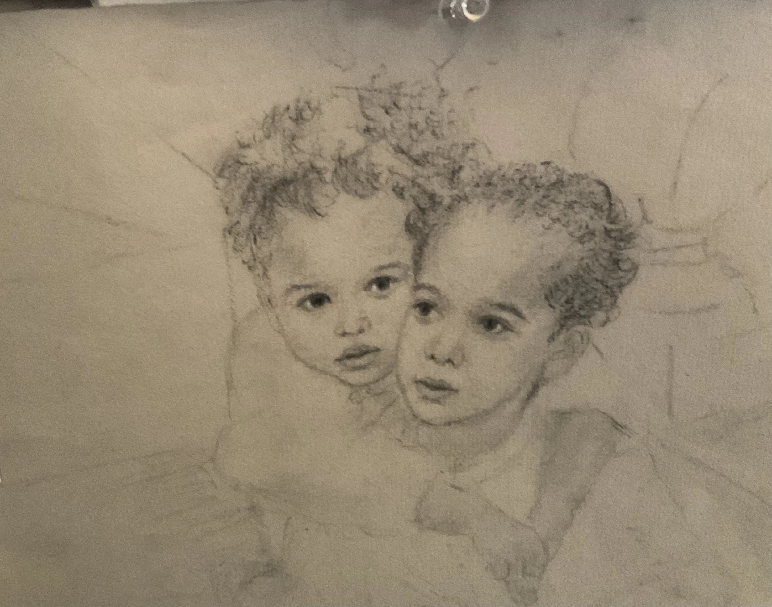 A pencil sketch of a young child's face with curly hair on a piece of paper.