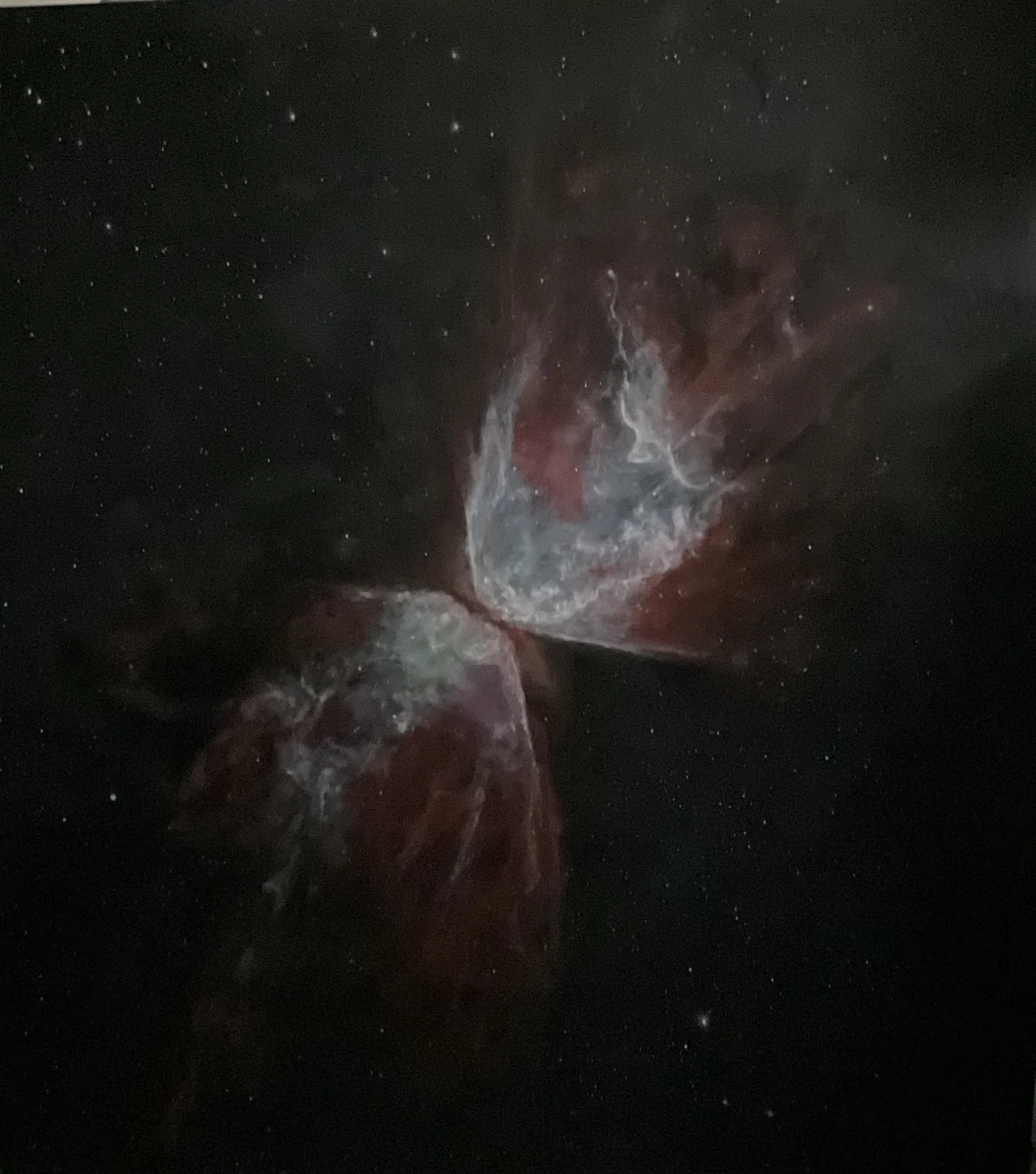 A photograph of a nebula in deep space, displaying a colorful cloud of gas and dust with stars scattered throughout the background.
