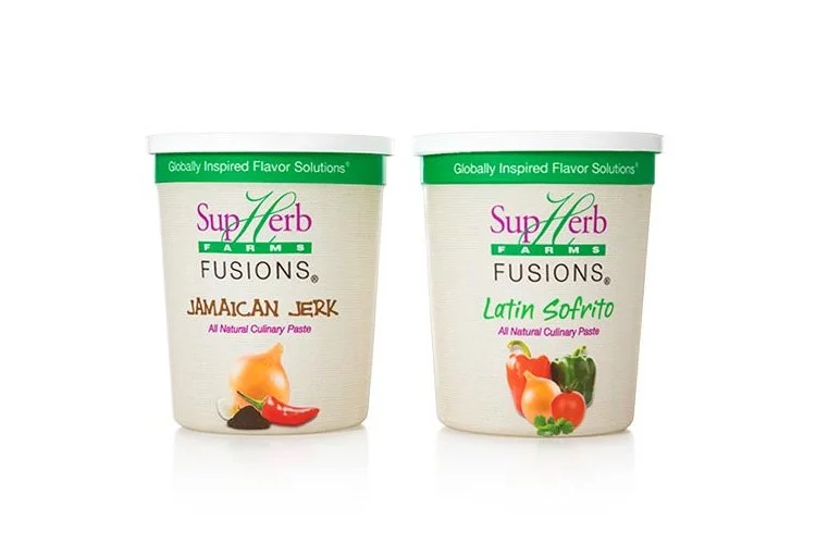 Two containers of SupraHerb Farms flavor solutions natural culinary pastes, Jamaica Jerk on the left and Latin Sofrito on the right, with images of ingredients like peppers, garlic, and herbs.