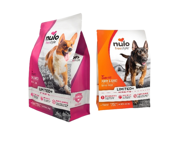 Two bags of Nulo Freestyle dog food, one pink with a corgi, and one orange with a German shepherd, set against a plain background.
