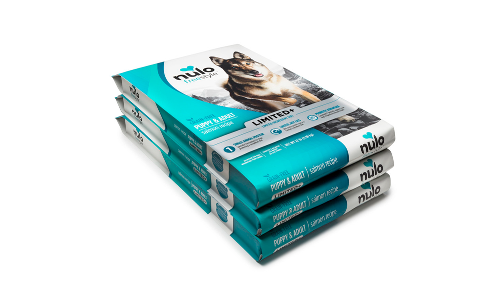 Three stacked packages of Nulo dog food, salmon recipe, designed for puppy and adult dogs.