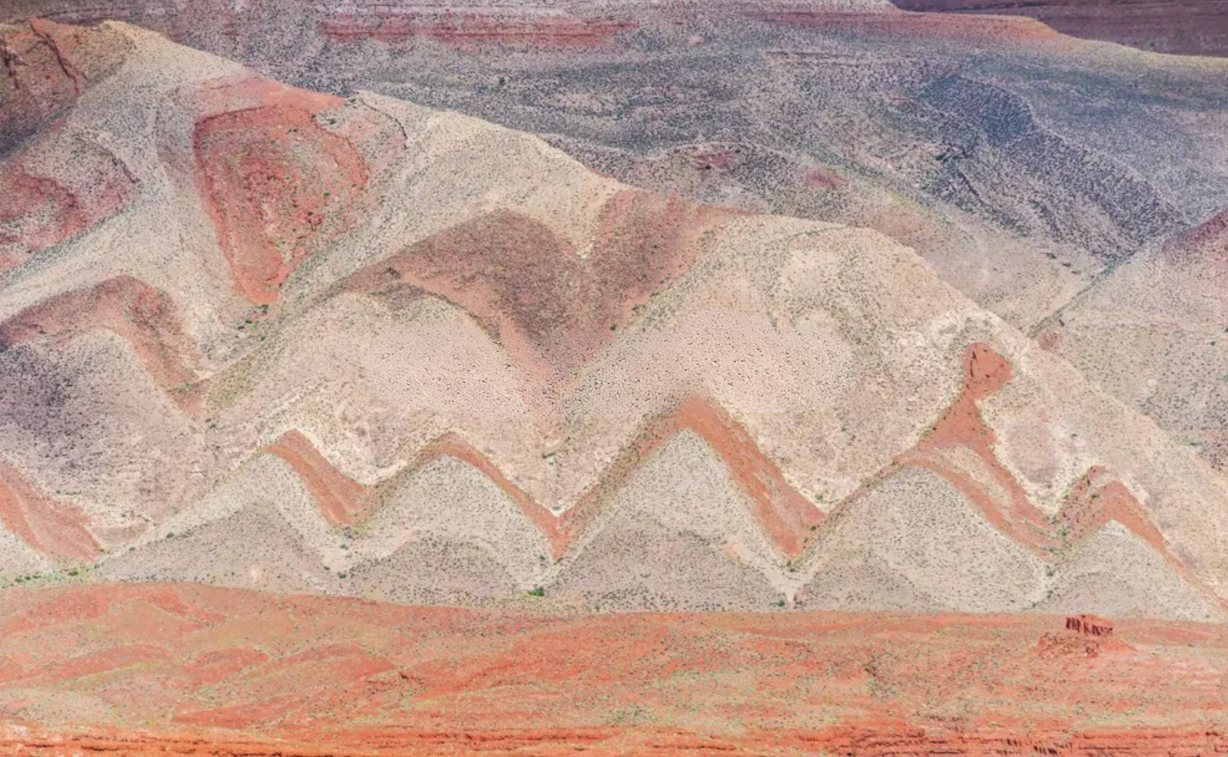 Aerial view of canyon mountains with layered rock formations and a dry landscape.