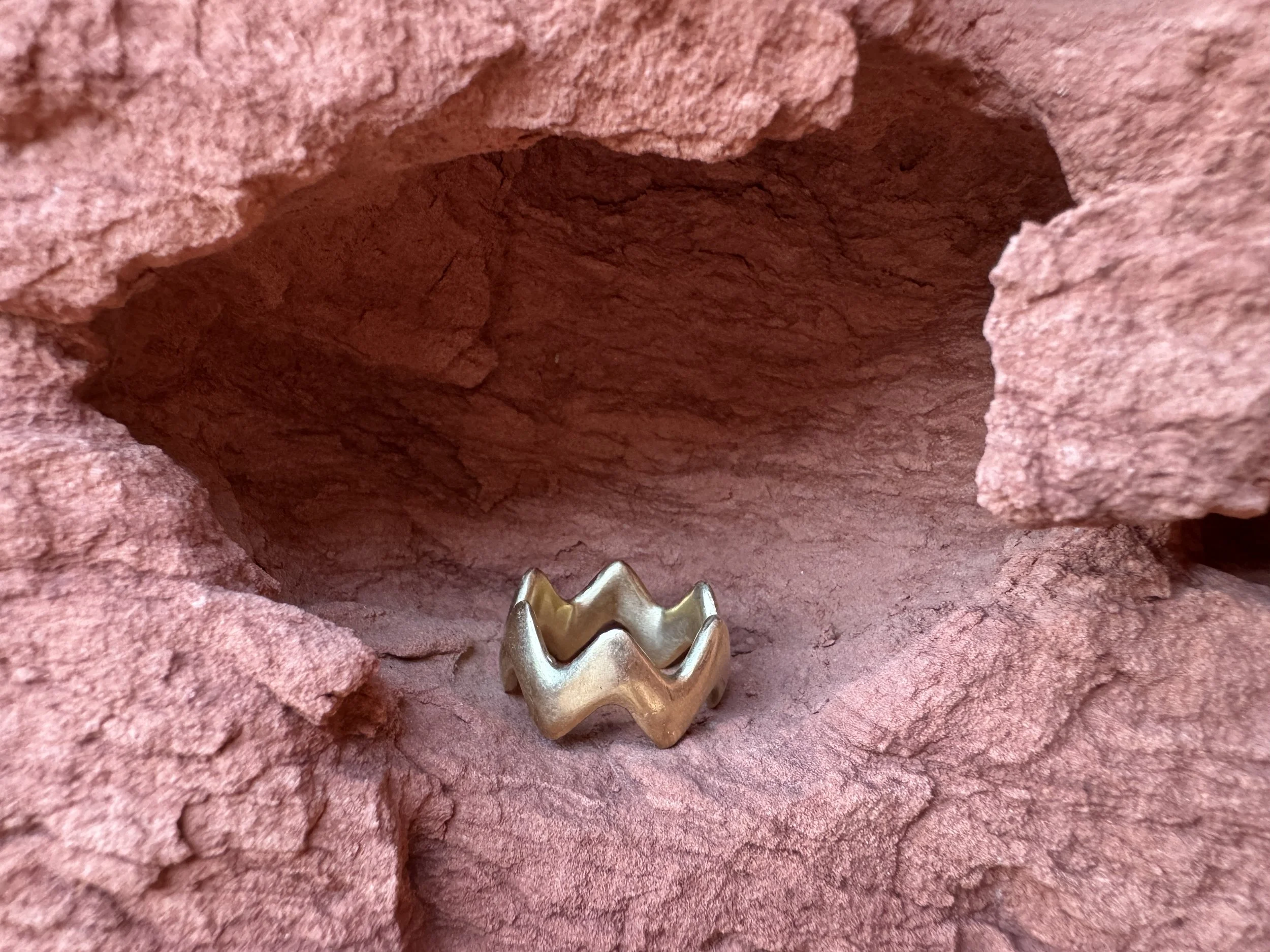 GemLost Desert ZigZag Ring in solid 18k gold resting inside a natural cavity in red rock.