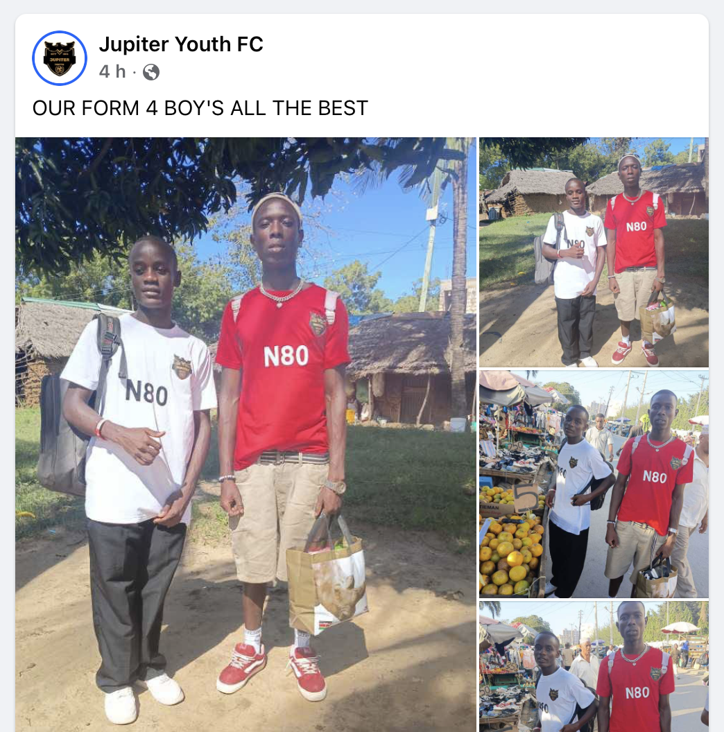 Two young boys standing outdoors in a rural area, one wearing a white t-shirt and the other wearing a red t-shirt with 'N80' printed on it. They are carrying bags and wearing backpacks, with trees and traditional houses in the background.