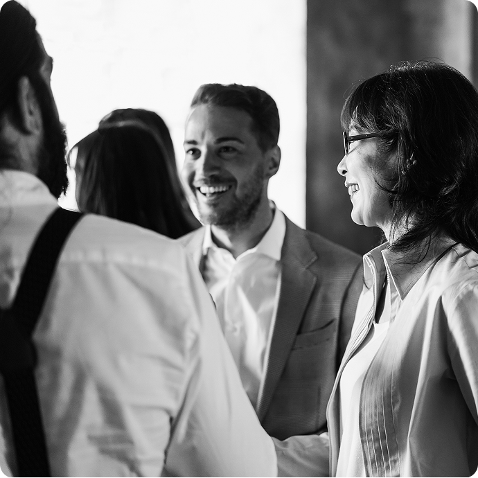Group of four professionals talking and smiling in a business setting, black and white photo.