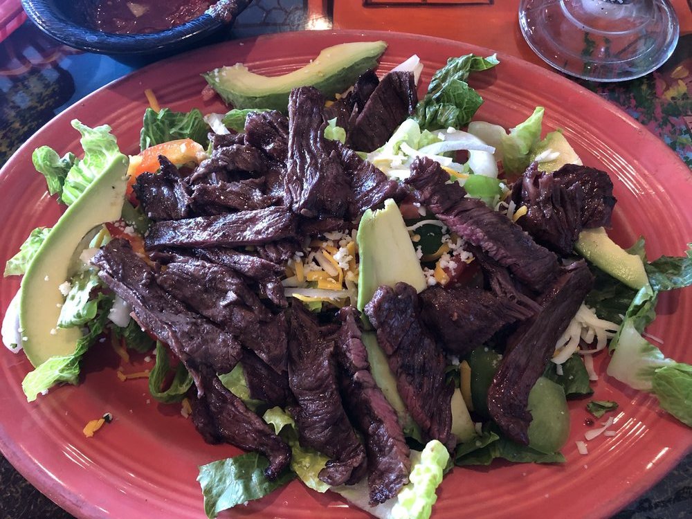 Dos Reales Salad topped with a mountain of carne asada cooked perfectly medium rare.