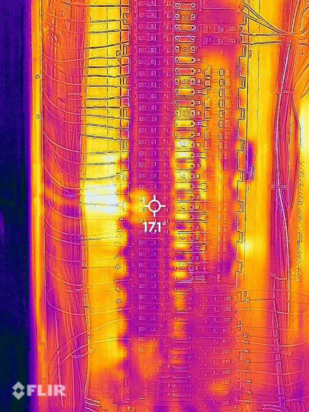 Infrared image of an electrical panel with warming components and wires, showing temperature variation.