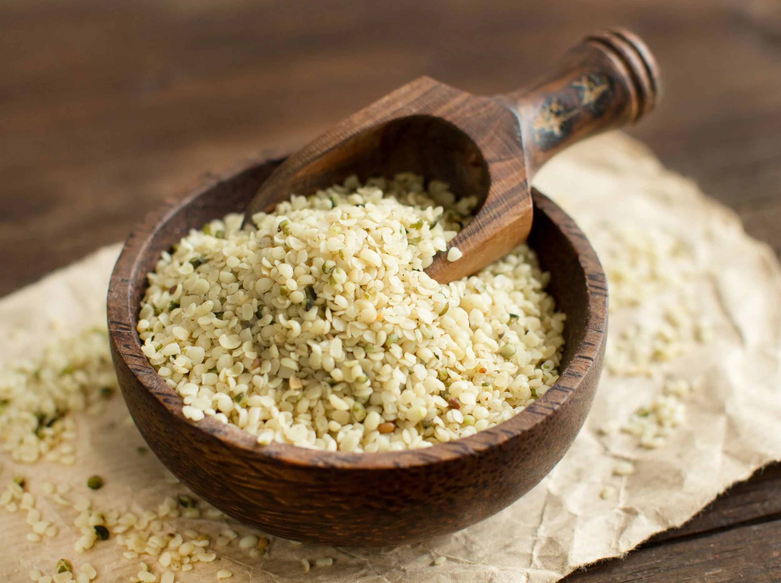 Close-up of a wooden scoop filled with chopped dried white onions in a wooden bowl on a wooden surface.