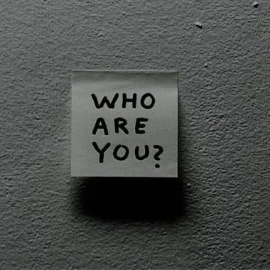 A soap note with the words 'Who are you?' written on it, mounted on a gray wall.