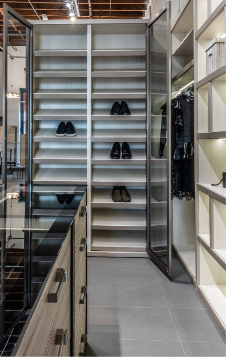 Empty shoe display shelves with a few pairs of shoes and some clothing on the side.