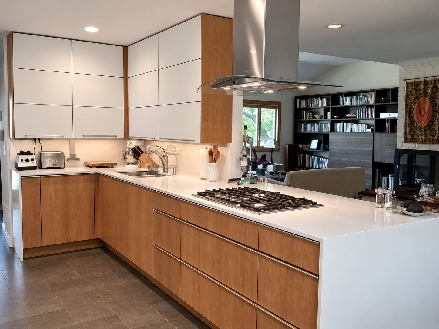 Modern kitchen with wooden cabinetry, white countertops, gas stove, and stainless steel range hood, with view into living room and bookshelf.