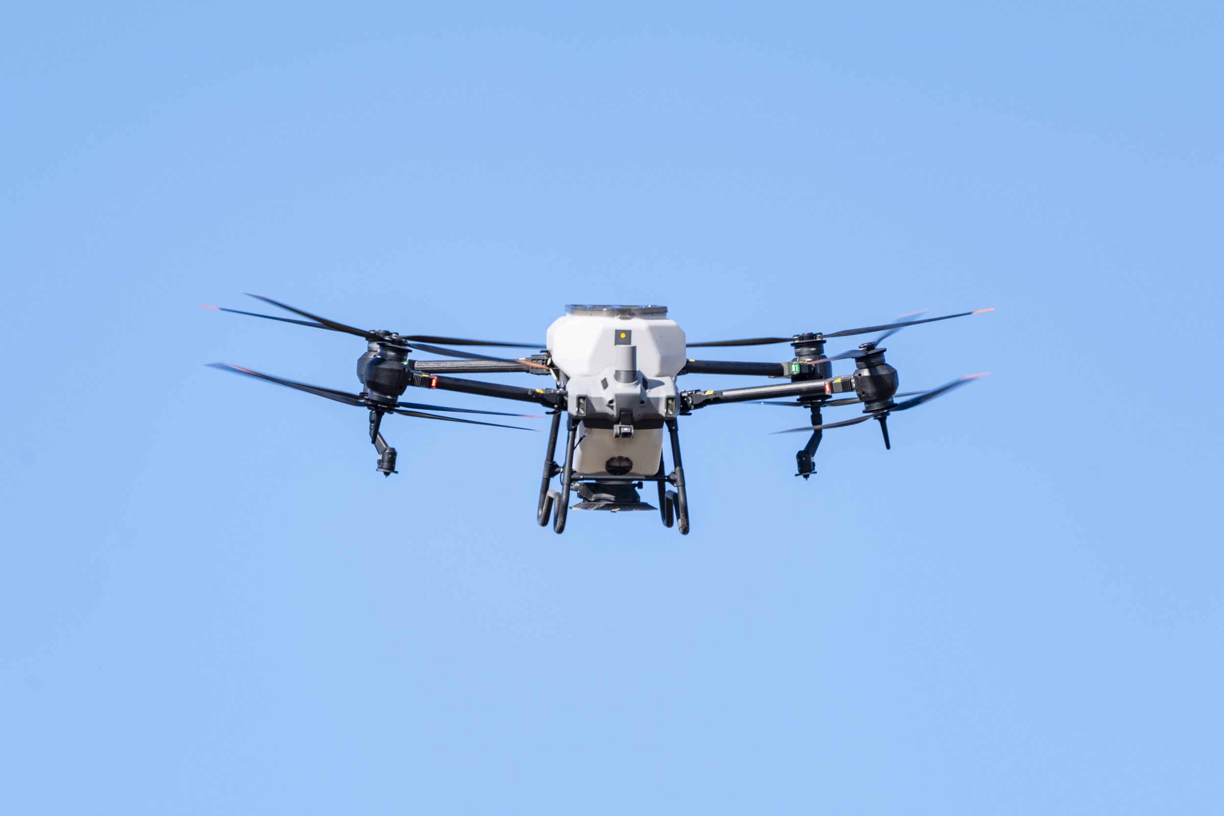 Aerial view of a drone flying in a clear blue sky.