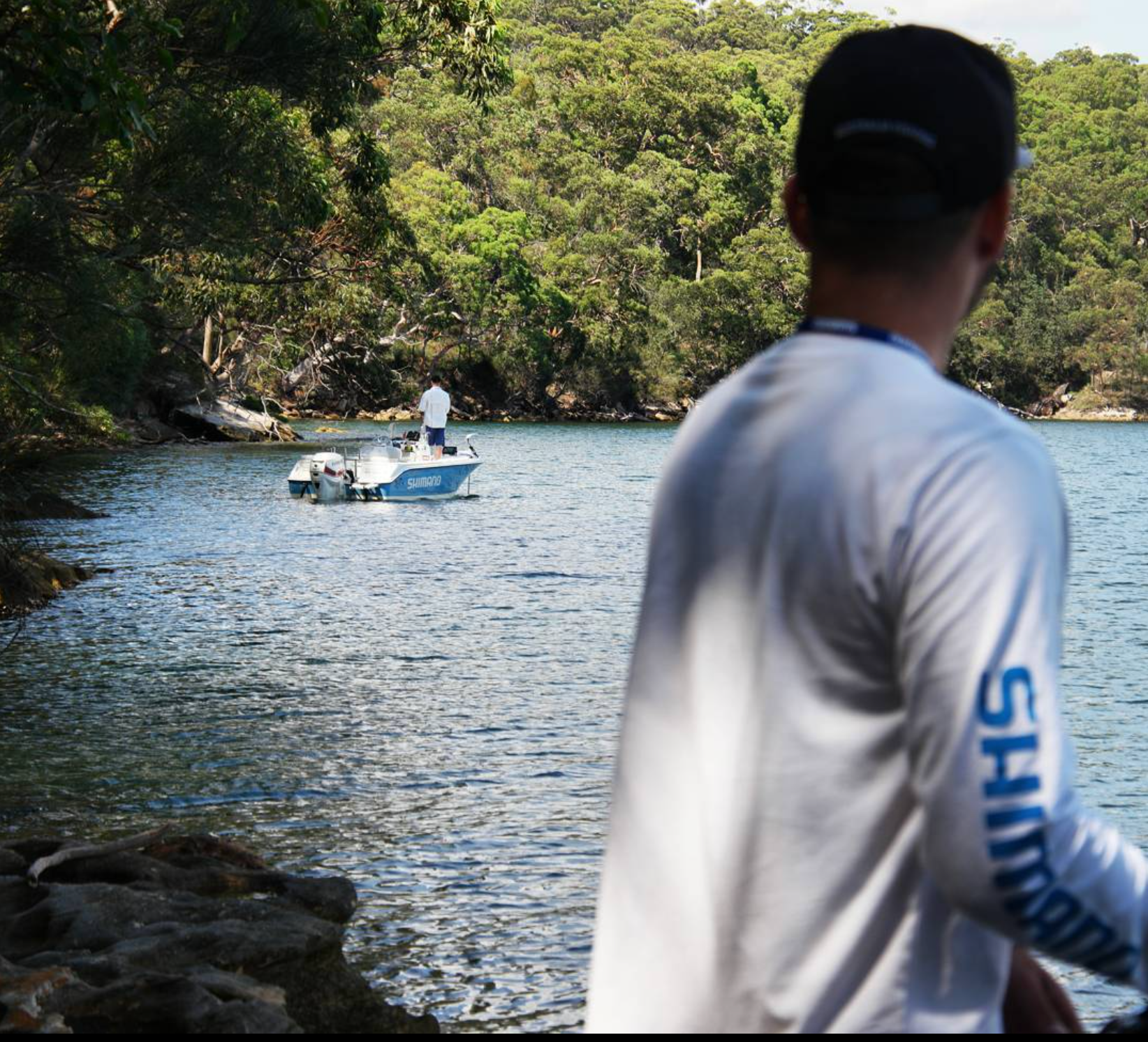 Behind the scenes on the Sedona shoot, with an angler in the foreground and a Shimano boat on a sheltered waterway.