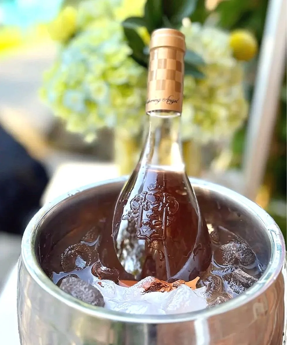 Close-up of a glass filled with ice and dark soda, with a plastic bottle of soda submerged in the drink.