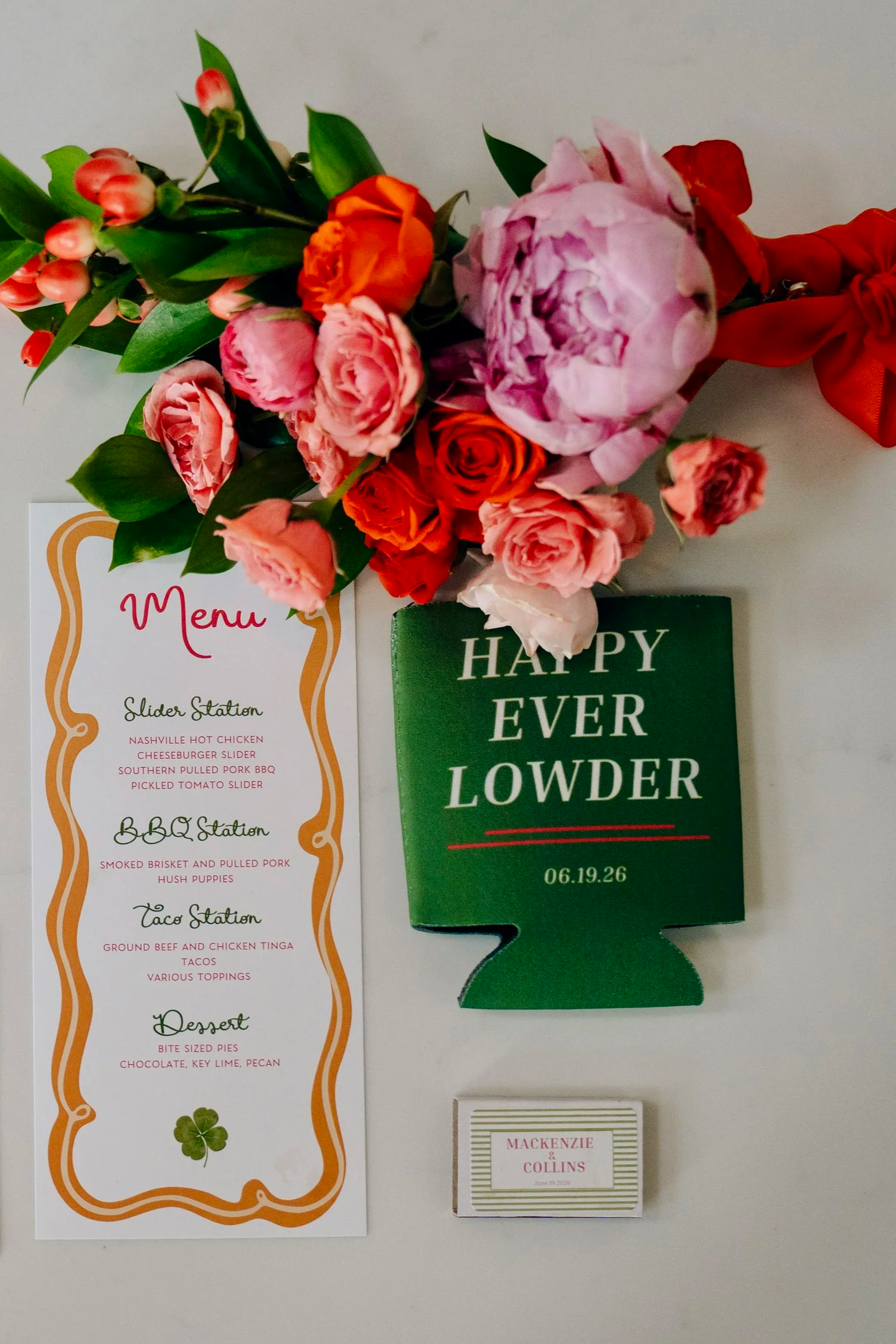 A flower bouquet with orange, pink, and white roses and pink peonies, attached to a red ribbon. To the left, a menu card with a scalloped border, listing items such as sliders, BBQ, tacos, and desserts. To the right, a green card with the text "HAPPY