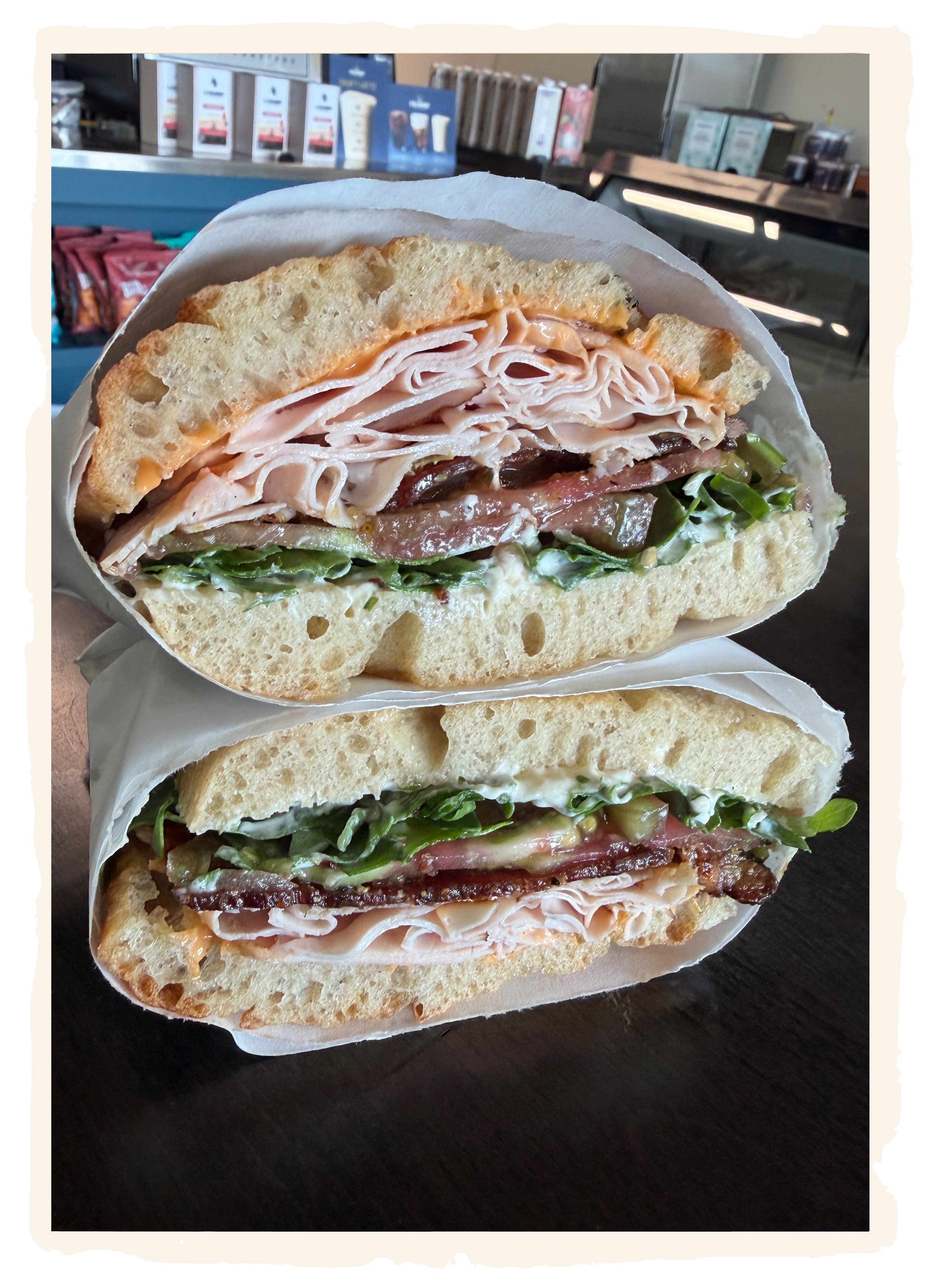 Close-up of three sub sandwiches filled with turkey, ham, lettuce, tomatoes, and other ingredients on toasted bread.