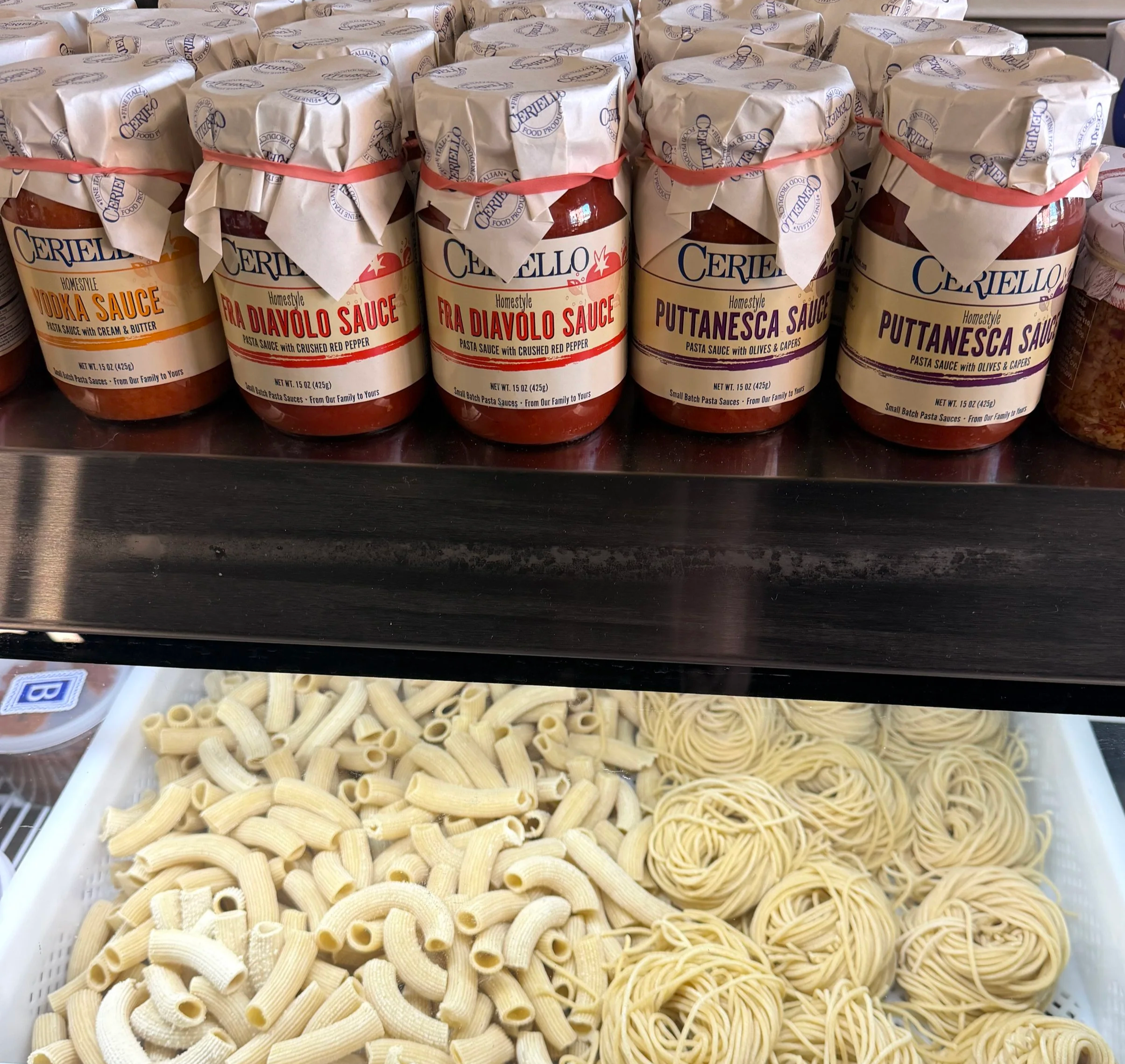 A display of various types of uncooked pasta in a store, including rigatoni, penne, and spaghetti, arranged in trays.