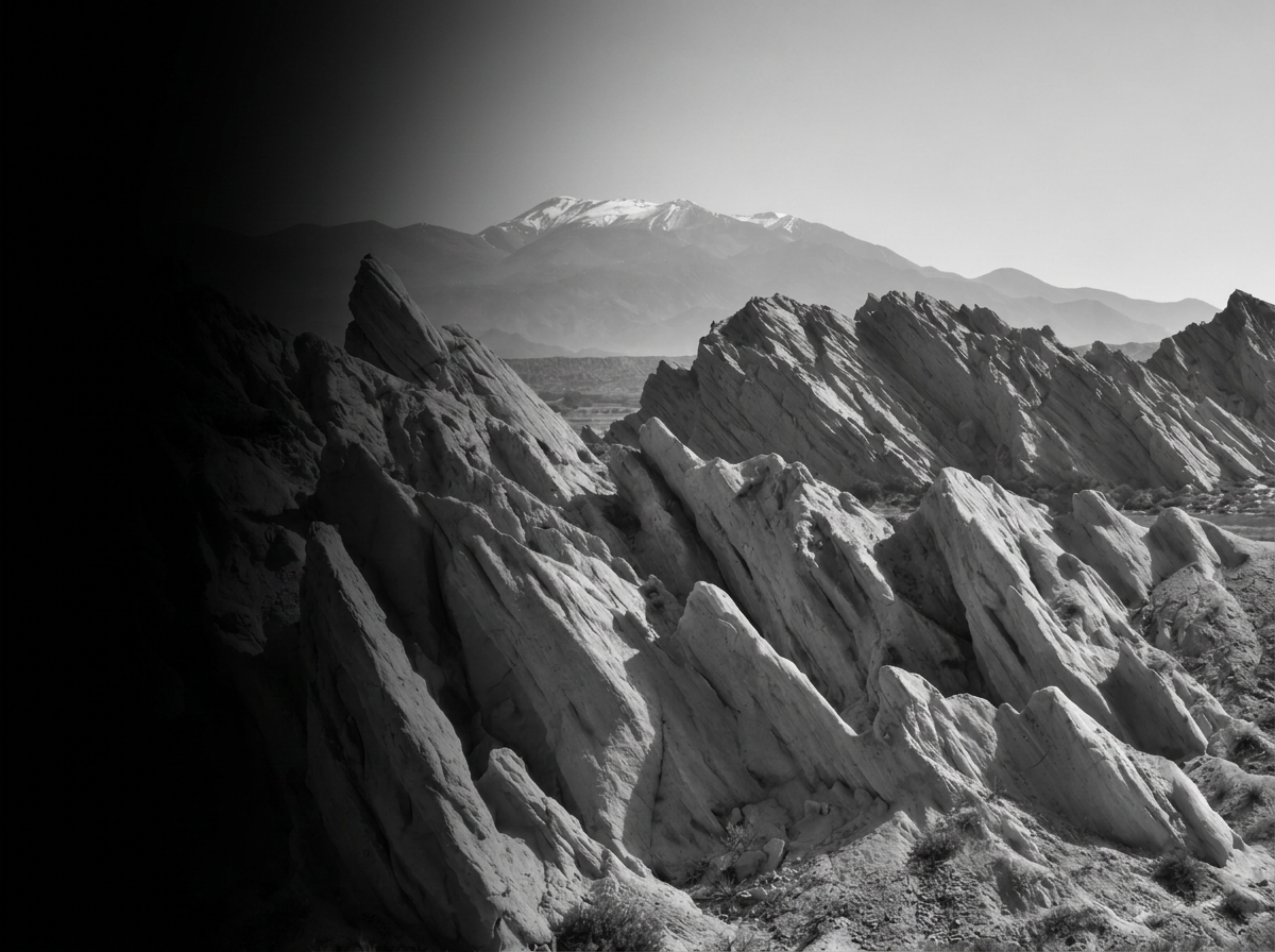 Black and white photograph of jagged rock formations with mountains in the background.