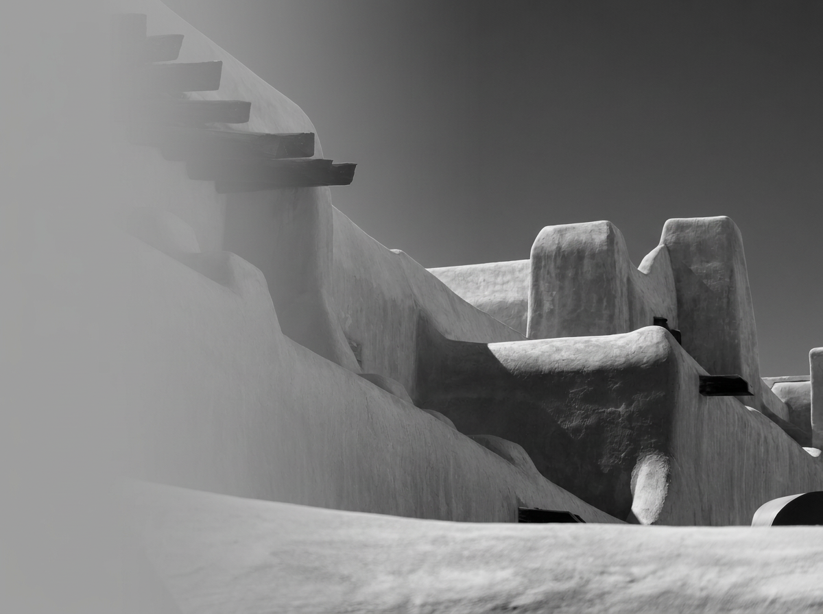 Black and white photo of unusual architecture with smooth white walls, rounded shapes, and rooftop structures, possibly a building on a hillside or a modern art installation.