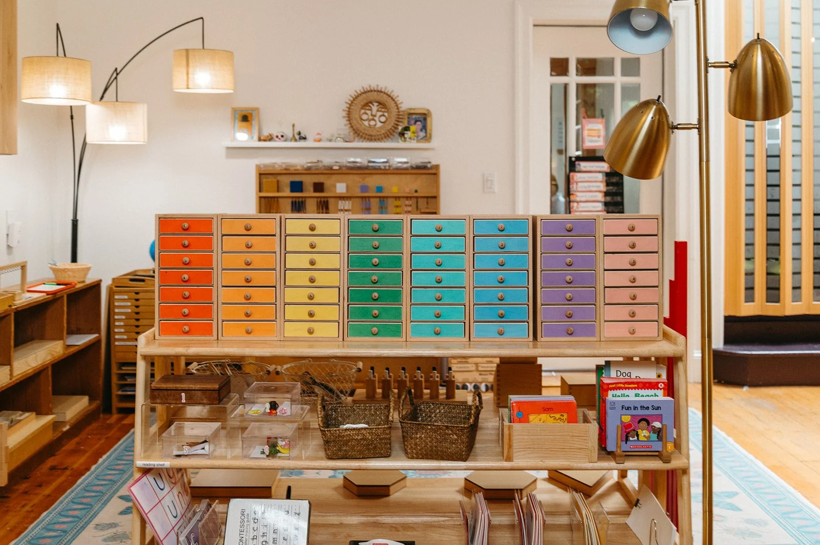 Art area with rainbow-colored drawers of paper and baskets of creative materials, part of Little Eden's arts-focused Montessori program