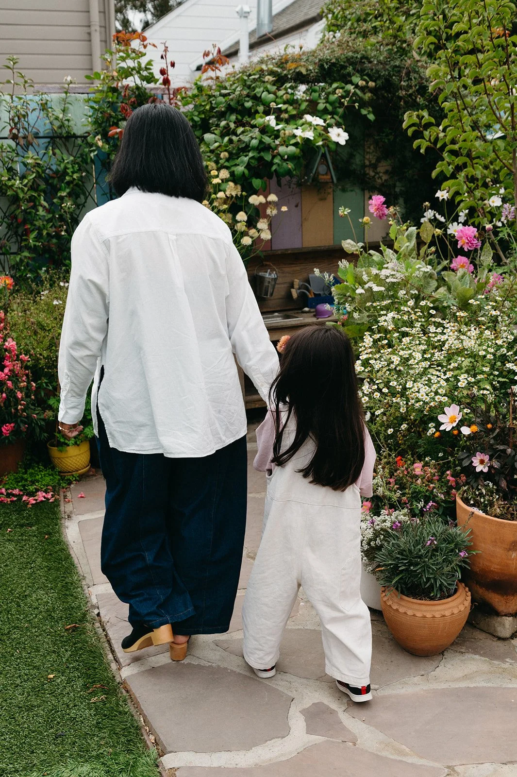Teacher and child walking together along a flower-lined garden path during outdoor learning