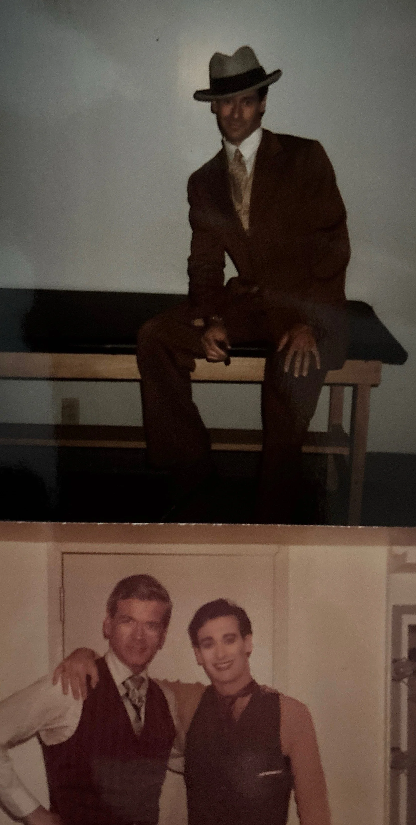 A man dressed in vintage clothing, including a hat and suit, sitting on a bench in a dark room.