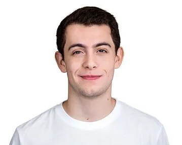 A young man smiling, wearing a white t-shirt, with short dark hair and light skin, against a plain white background.