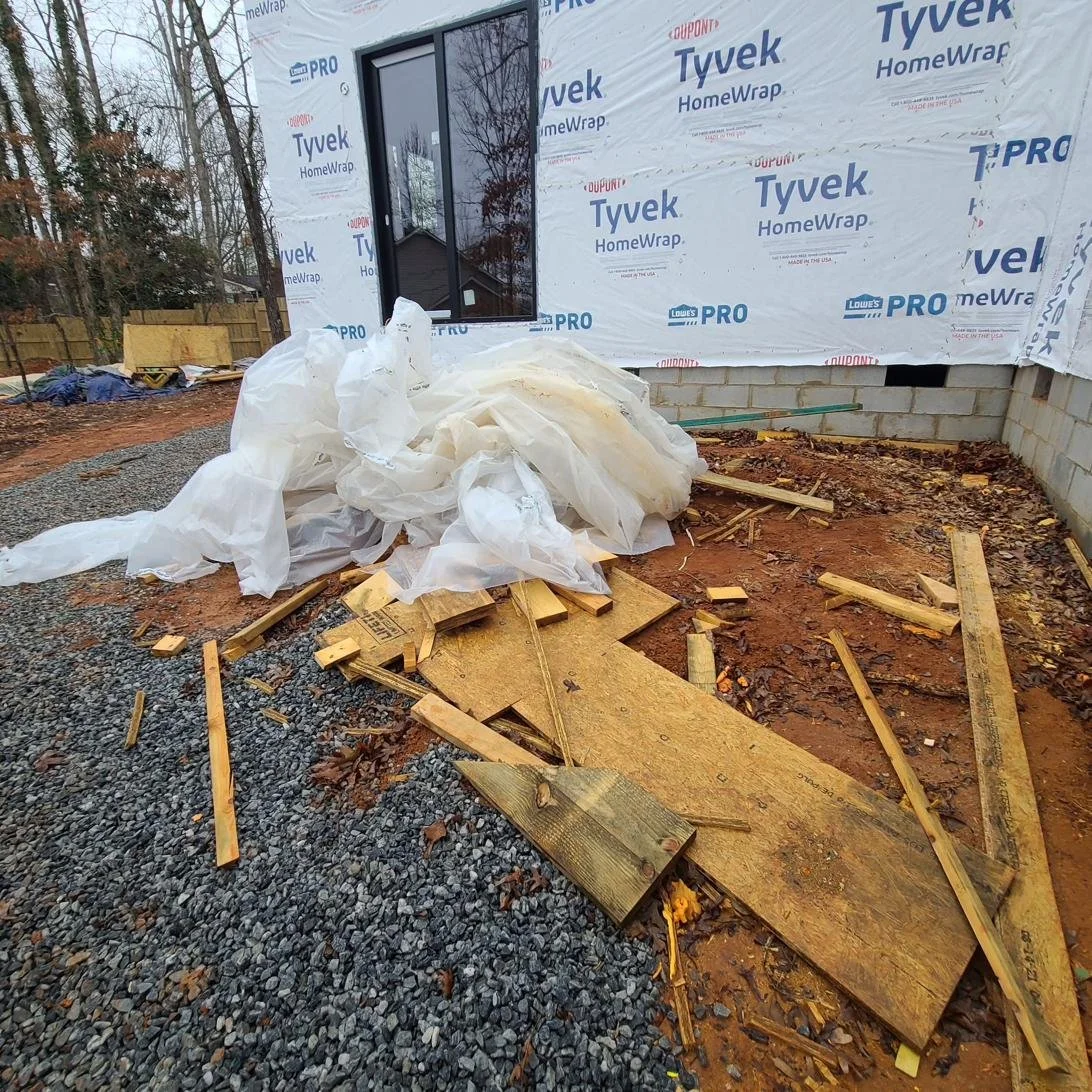 Construction debris removal in Memphis, TN — scattered wood planks, plastic sheeting, and building materials cleared from a job site.