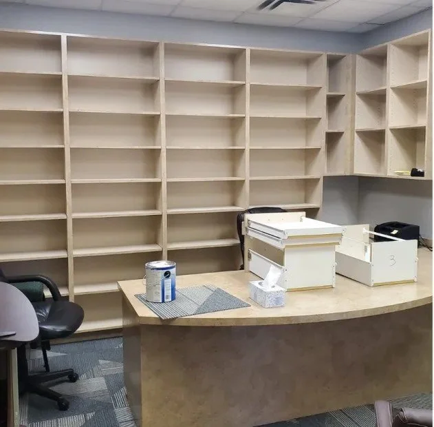 Empty office space after a commercial junk removal job in Memphis, TN, with bookshelf and desk cleared of clutter.