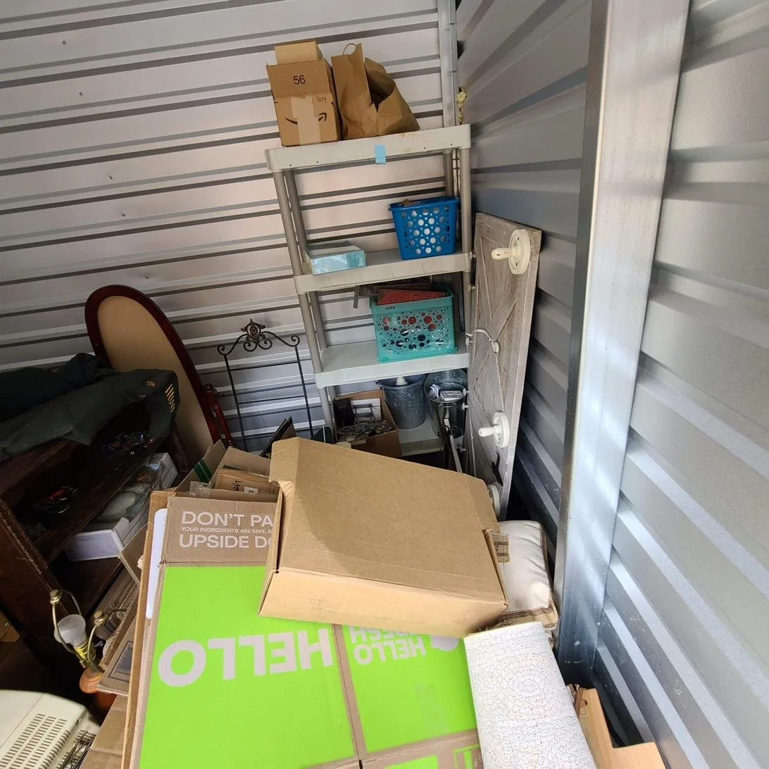 Storage unit packed with boxes, bins, and furniture before a storage unit cleanout in Memphis, TN.