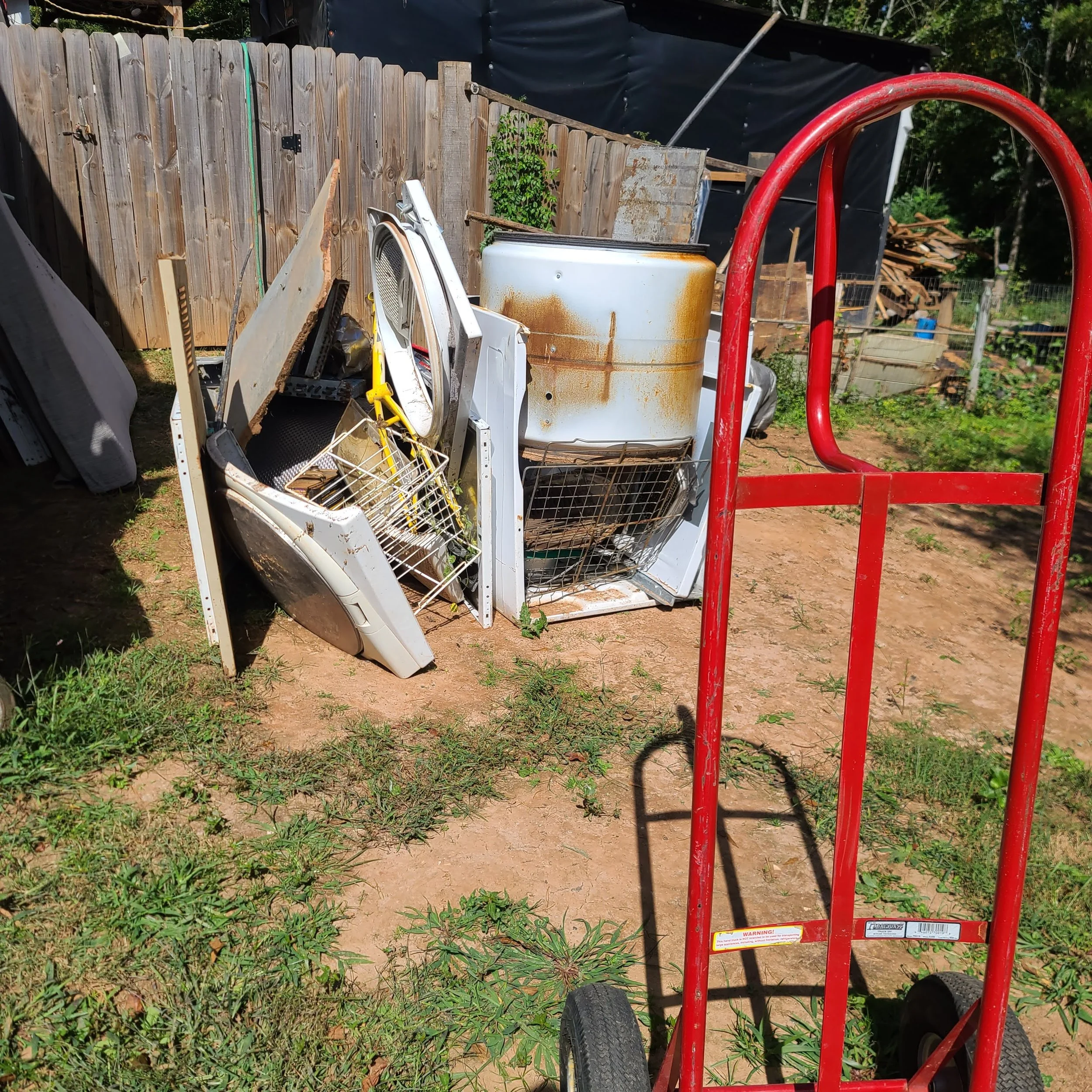 Yard full of discarded appliances and debris before a yard cleanup and junk removal job in Memphis, TN.