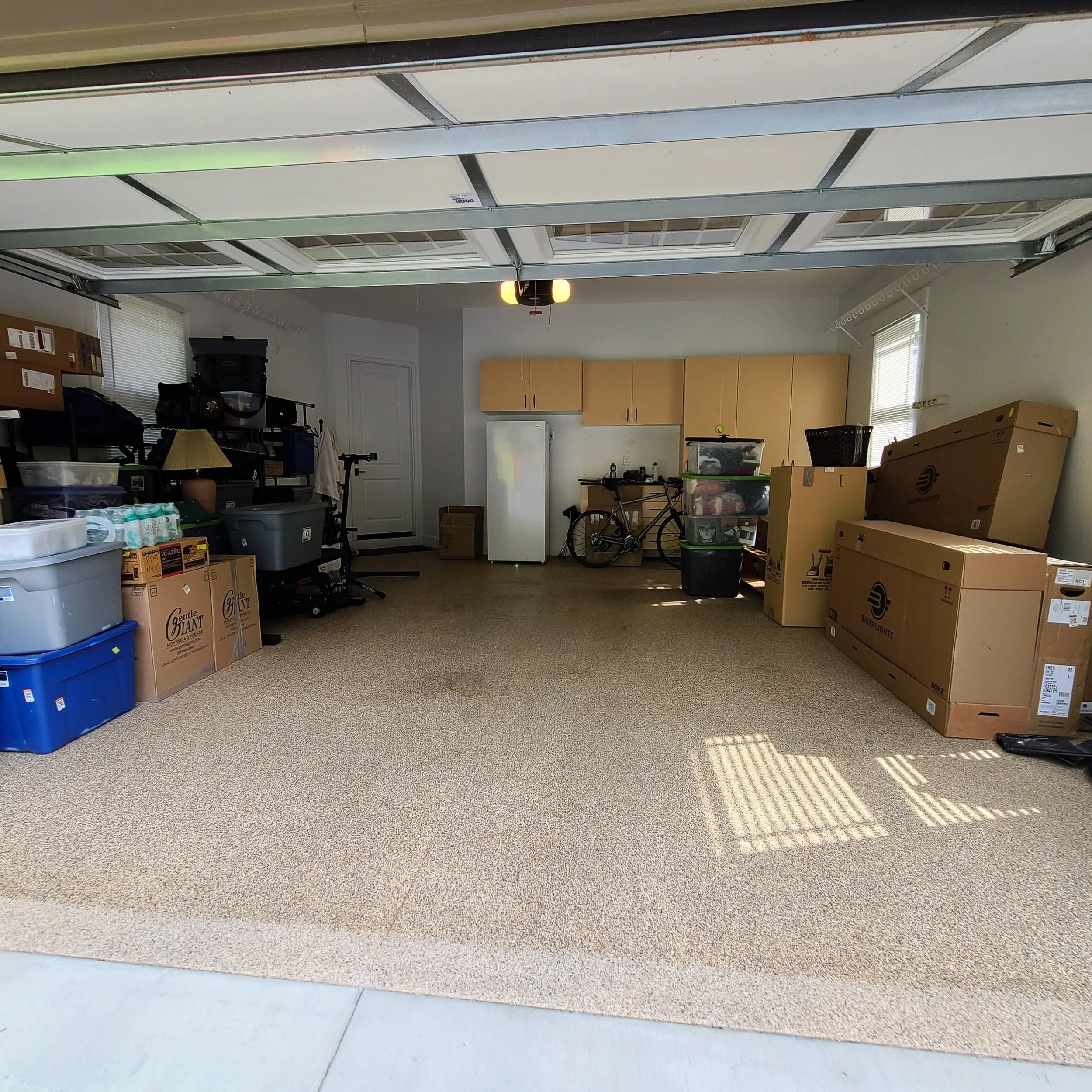 Cluttered garage with storage bins and a bicycle before a residential junk removal service in Memphis, TN.