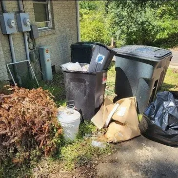 Overflowing trash bins and bagged debris outside a property before a residential junk removal pickup in Memphis, TN.