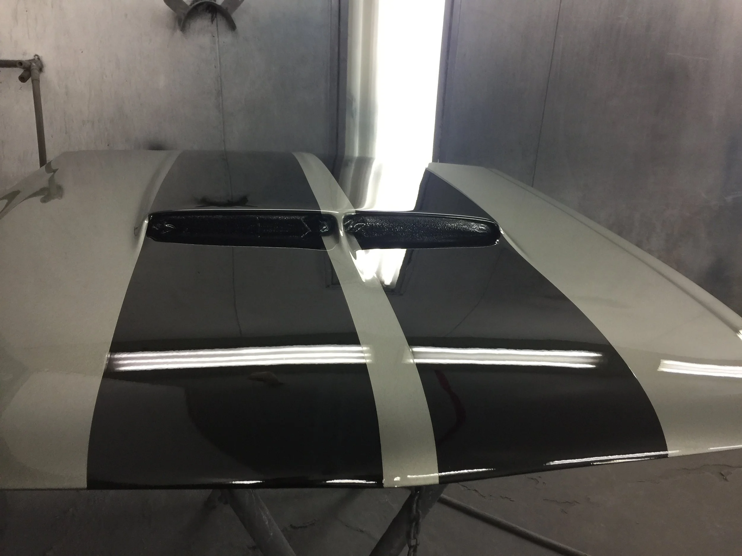Close-up of a silver and black motorcycle with a gray and black checkered floor in the background.