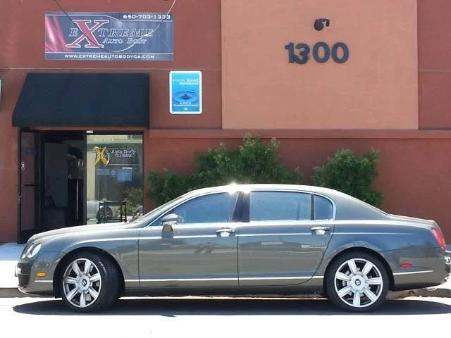 Gray sedan parked outside a building with a sign that reads 'Extreme Auto Body' and the number 1300.