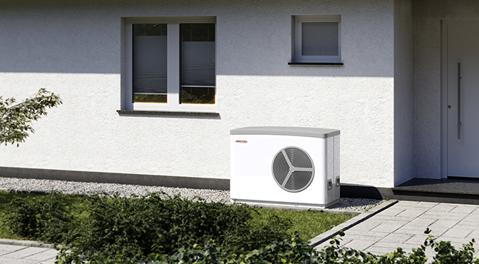 Outdoor view of a white building with black trim, showing two windows and a door, with an air conditioning or heating unit outside on the ground near a paved walkway and bushes.