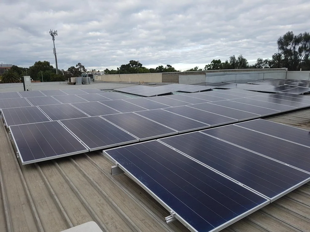 A rooftop covered with multiple solar panels installed in rows under a cloudy sky.