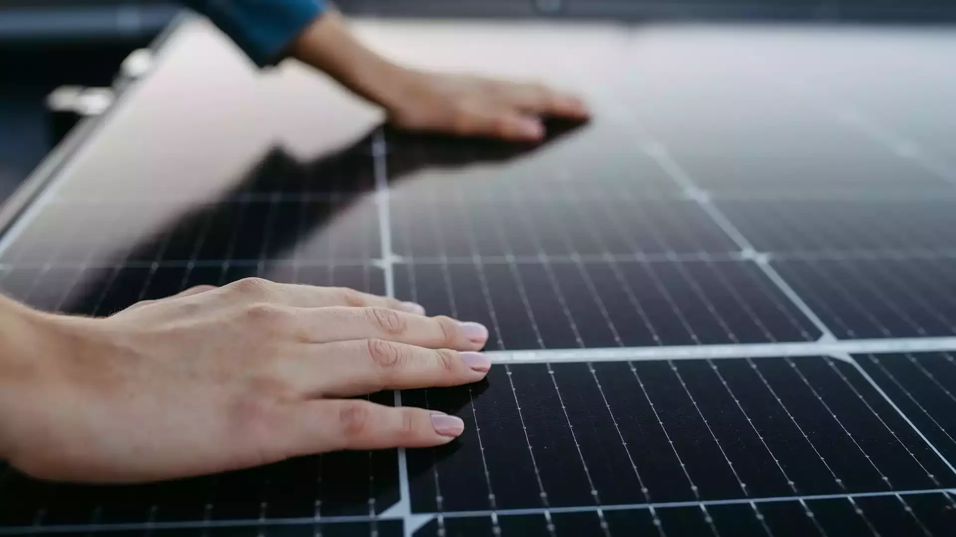 Close-up of two hands installing or inspecting a solar panel.