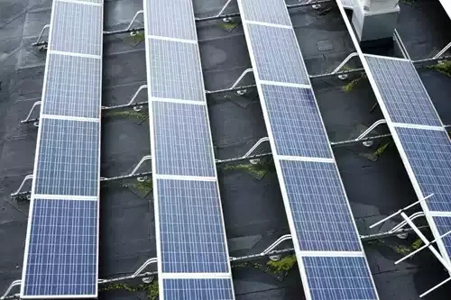 Multiple solar panels installed on a rooftop with cables connected underneath.